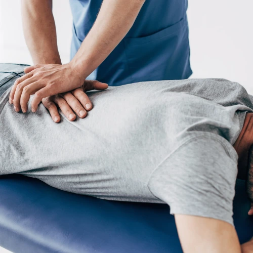 Doctor in scrubs administering chiropractic treatment to man in grey t-shirt - back pain from losing weight chiropractic care in Hiram, GA.